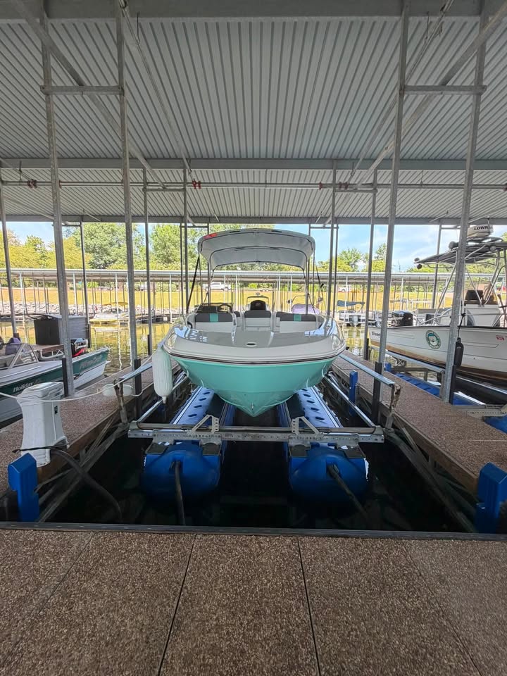 Boat on a HydroHoist boat lift with blue flotation tanks in a covered marina slip